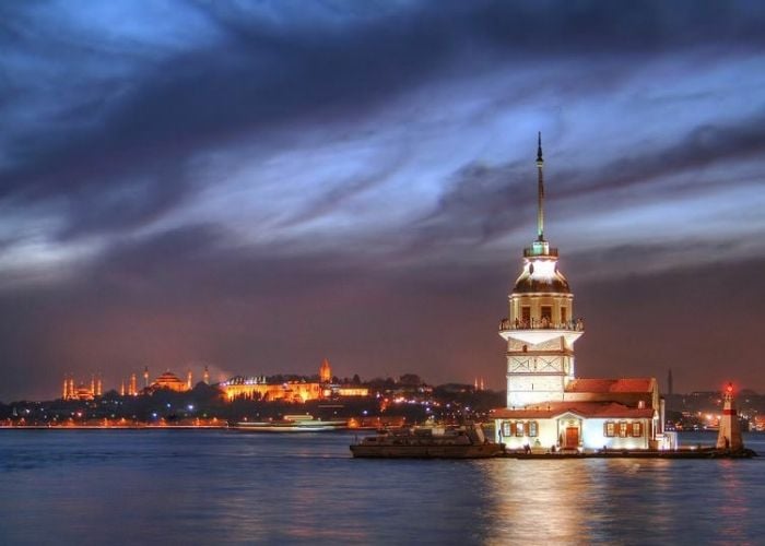 The Maiden's Tower lit at dusk with the old city skyline glowing behind
